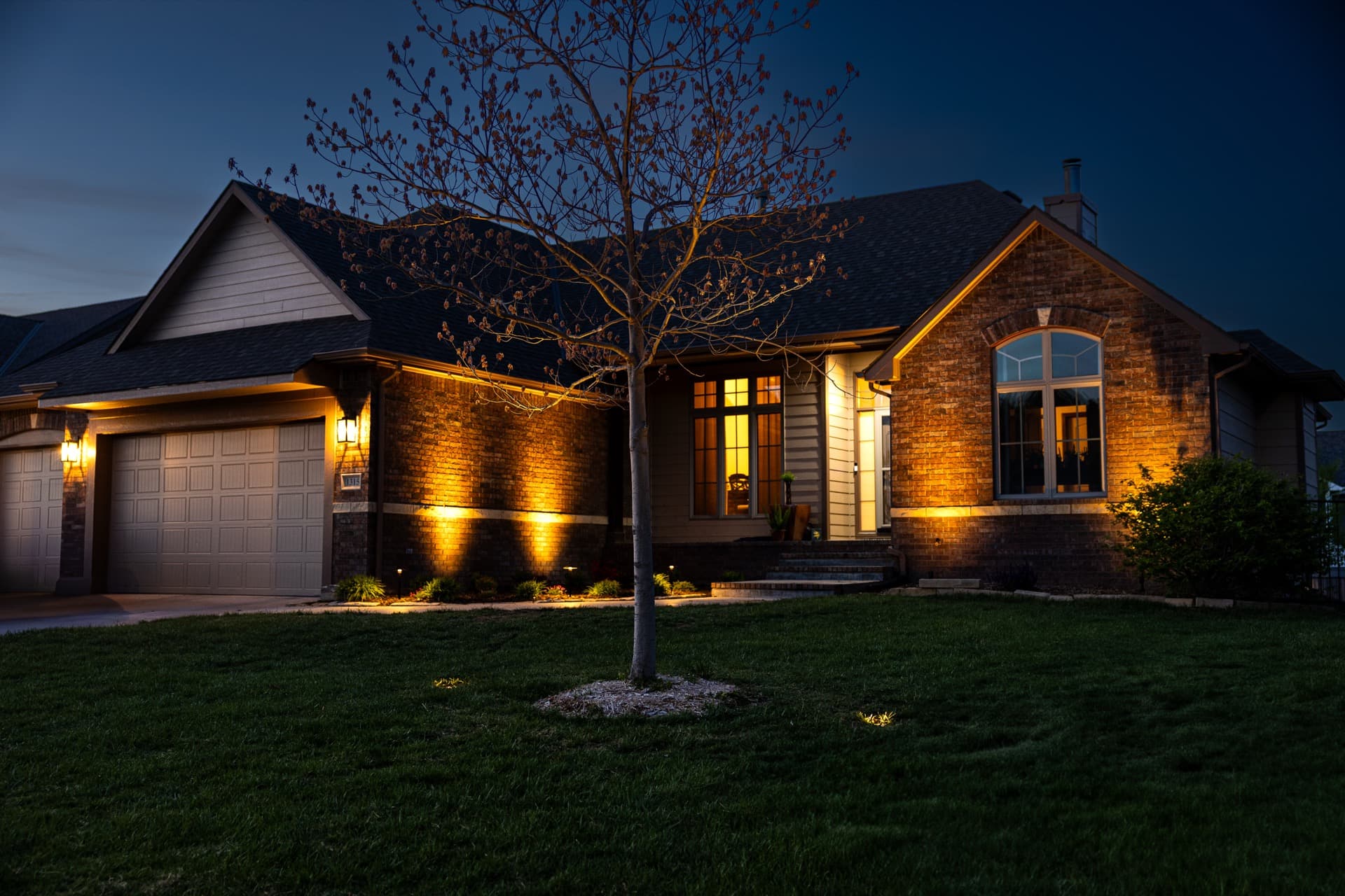 Warm white lighting grazing the brick facade of a Wichita home