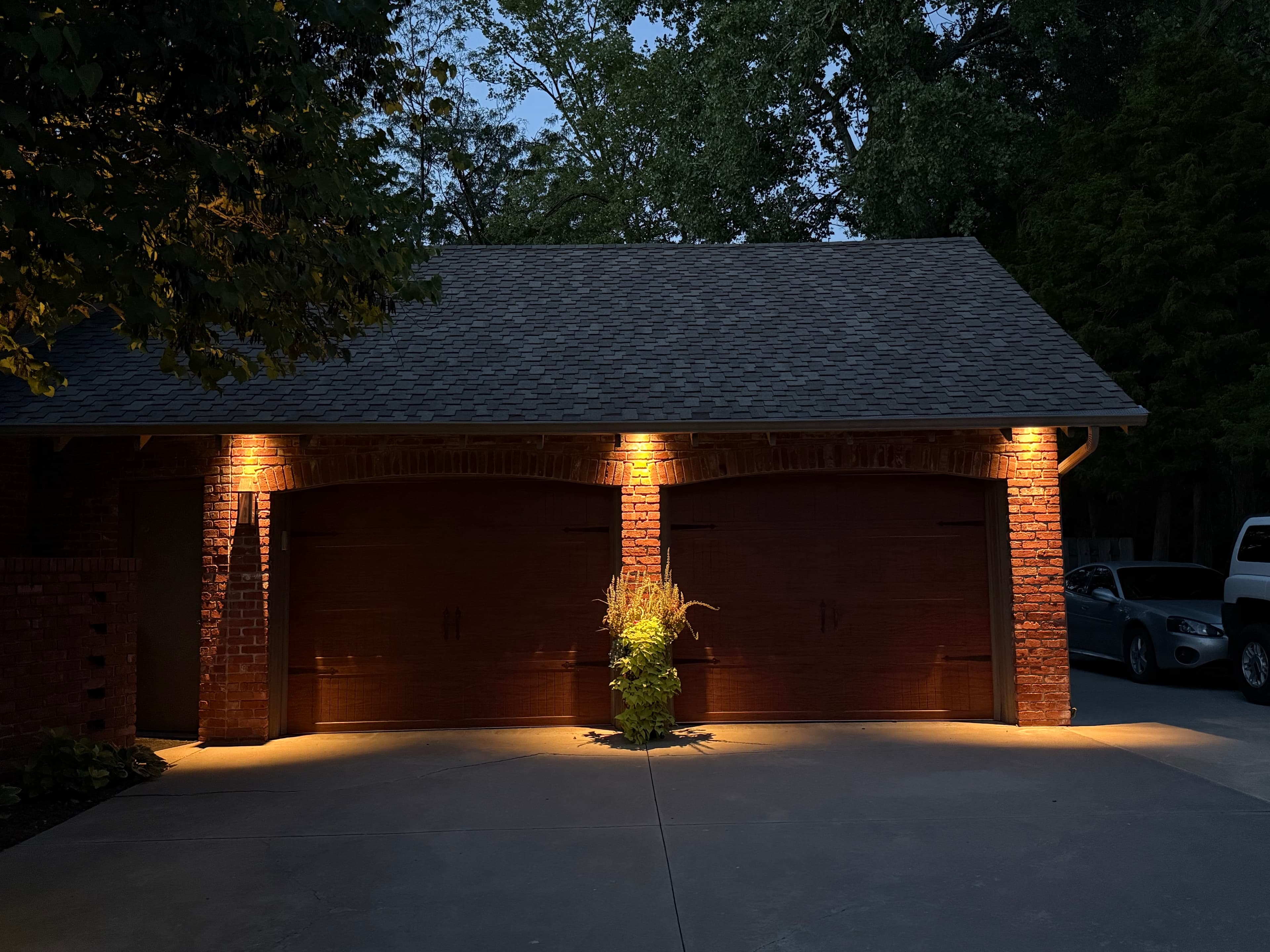Garage and driveway lit by low-voltage landscape lighting at night